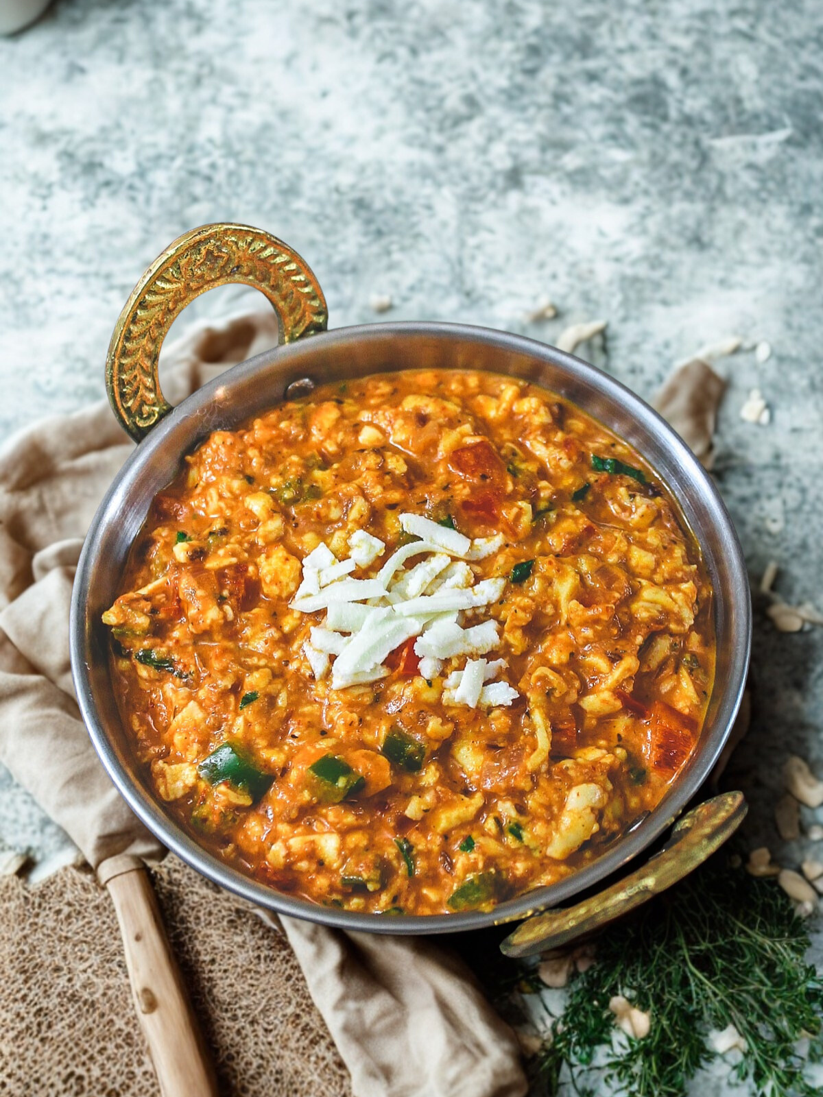Paneer bhurji in gold-handled kadhai on linen cloth with grated cheese garnish
